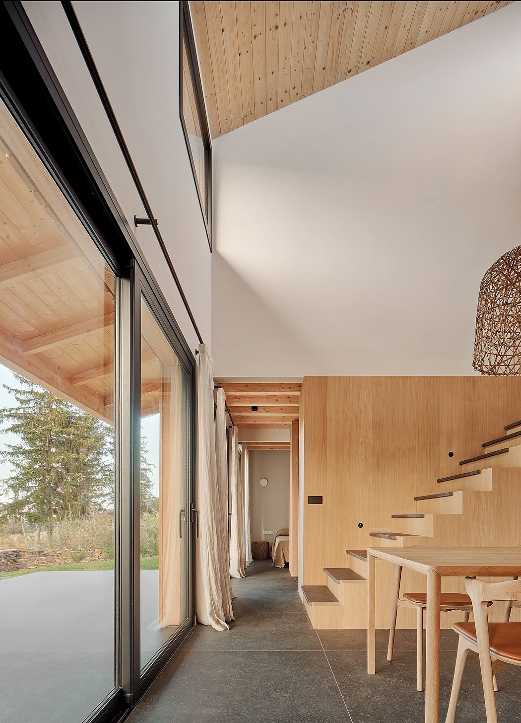 Modern, minimalist interior with wood paneling, large windows, and a sleek staircase.