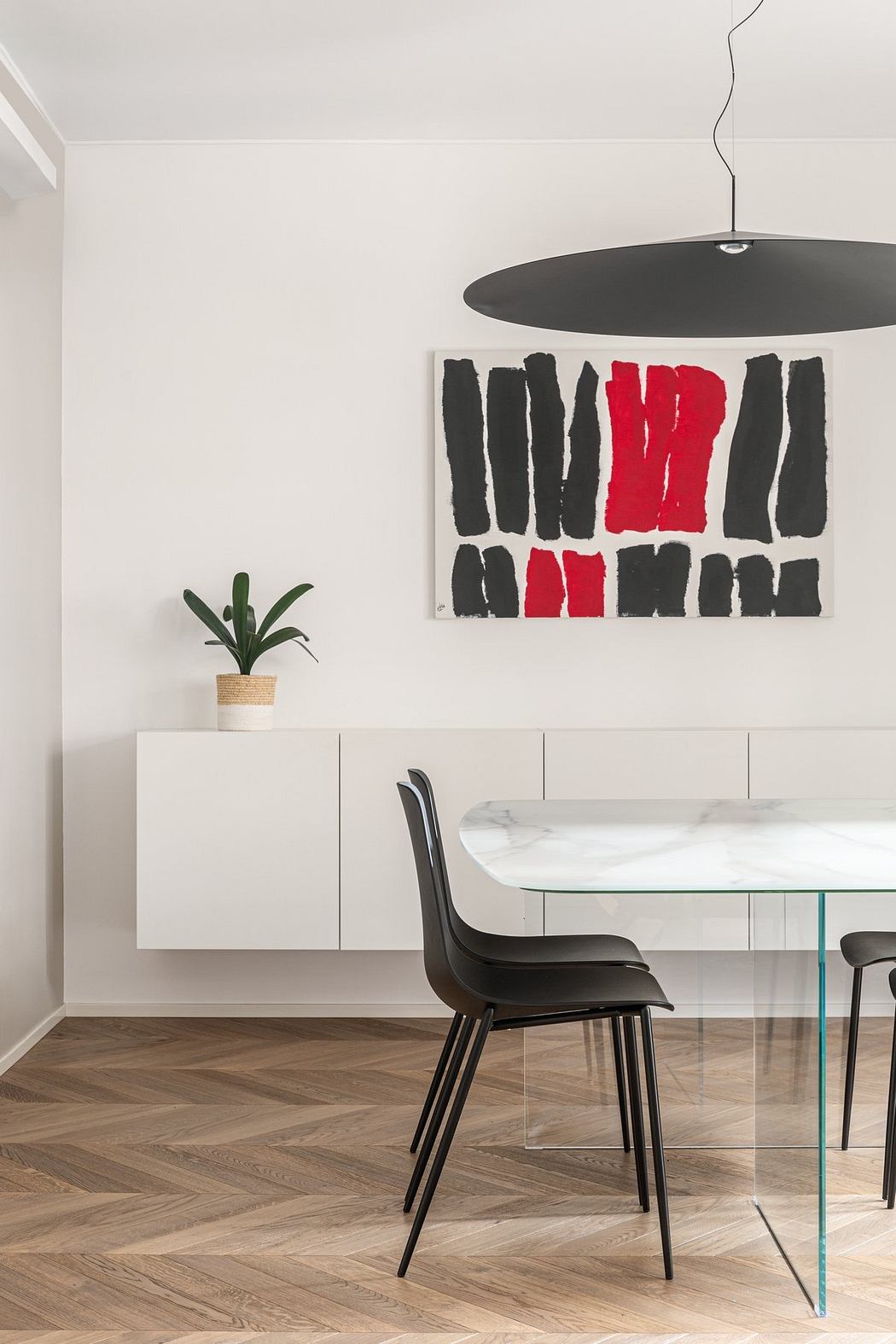 Modern, minimalist dining room with abstract wall art, glass table, and black chairs.