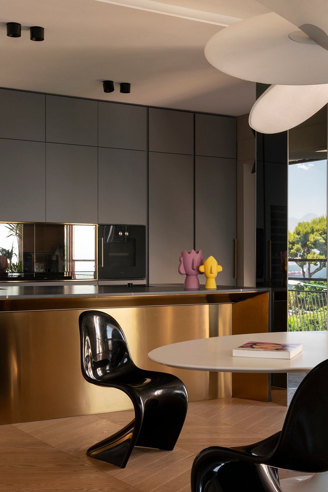 Sleek, modern kitchen with dark cabinetry, gold accents, and minimalist decor.