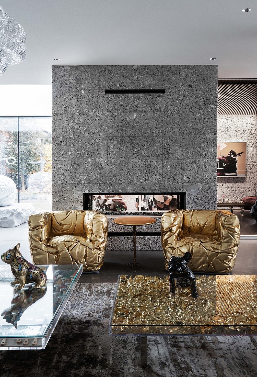 Sleek, modern living space with satin gold accents, stone fireplace, and glass-topped coffee table.