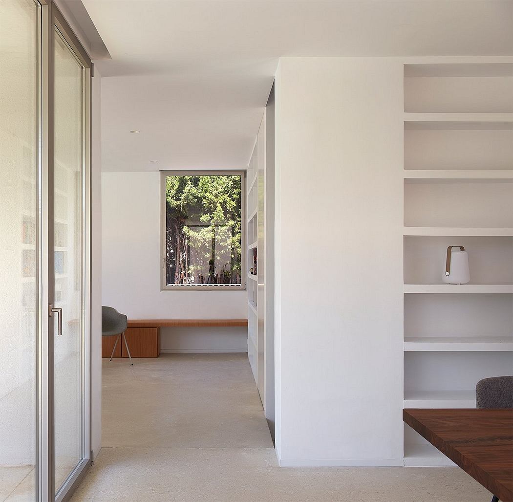 A modern, minimalist interior with a large window offering a view of the surrounding greenery.