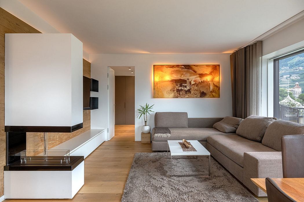 Spacious living room with warm-toned artwork, modern fireplace, and panoramic window.