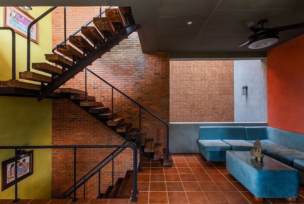 Rustic staircase, brick walls, colorful furnishings, and tiled flooring create a cozy, modern interior.