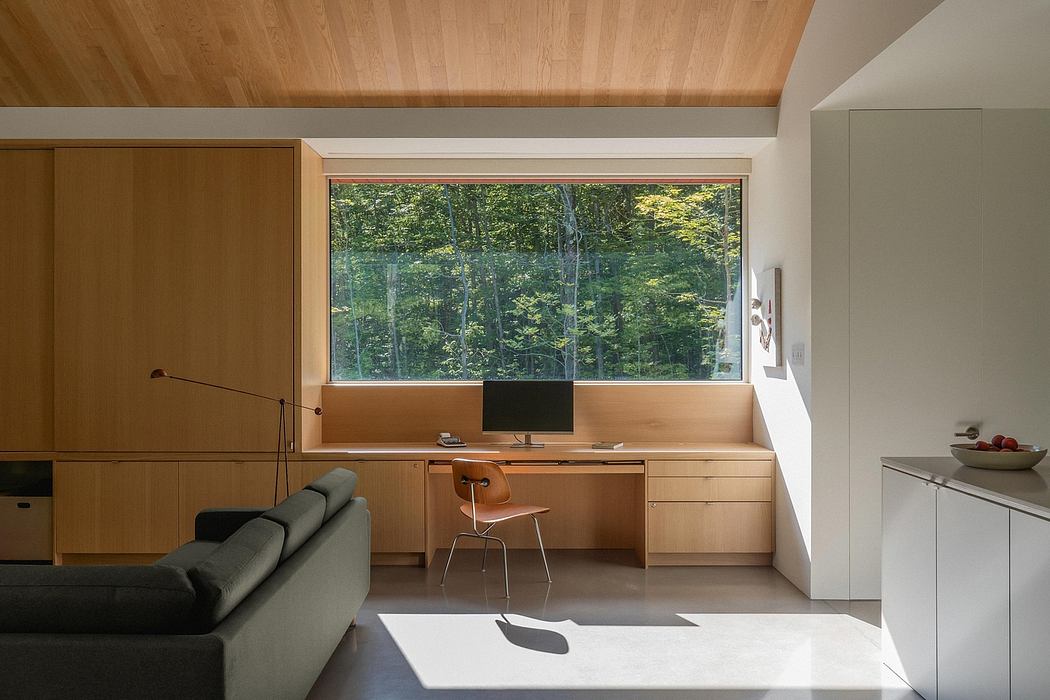 Spacious modern interior with wood paneling, built-in desk, and expansive forest view.