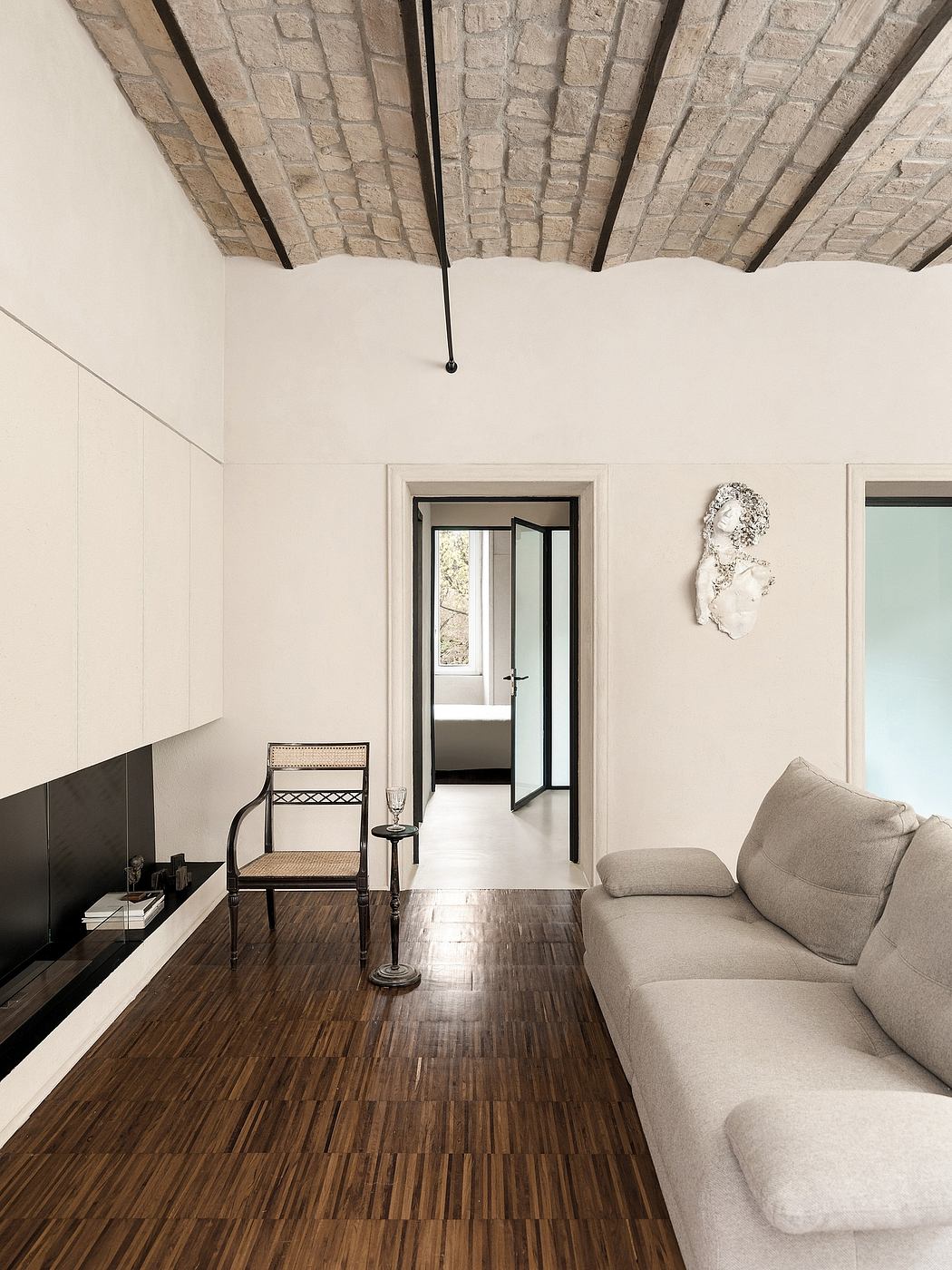 Minimal space with textured brick ceiling, wooden floor, and sleek furniture.