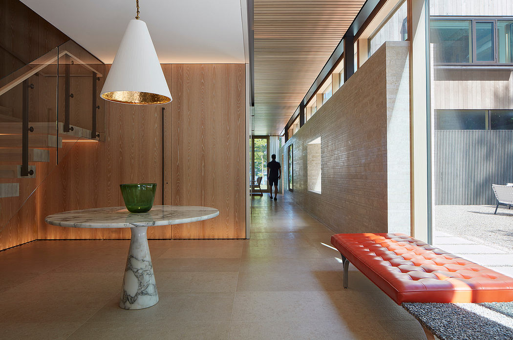 Sleek, modern interior with wood paneling, marble table, and red leather bench.