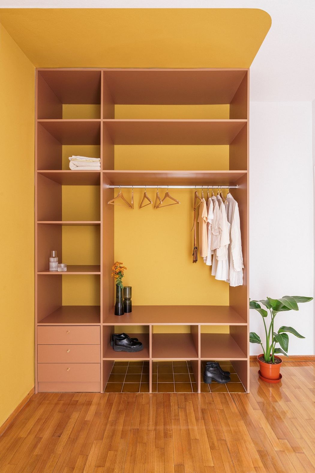 Minimalist wardrobe design with recessed shelves, hanging rod, and storage compartments.