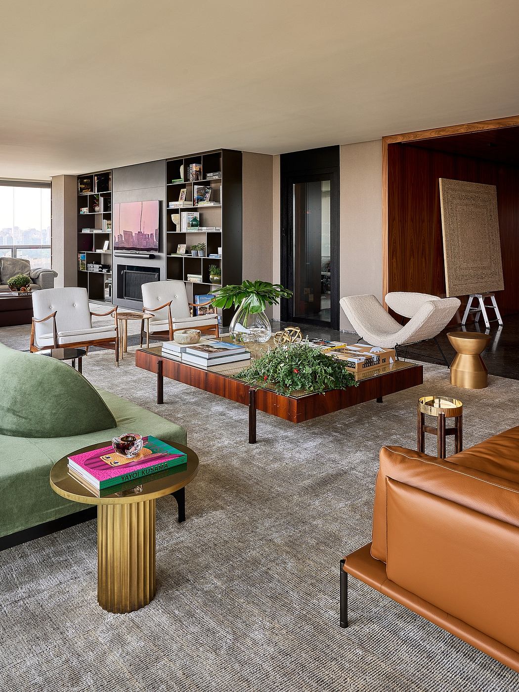 Warm, modern living room with custom built-in shelving, greenery, and a mix of wood, leather, and metallic accents.