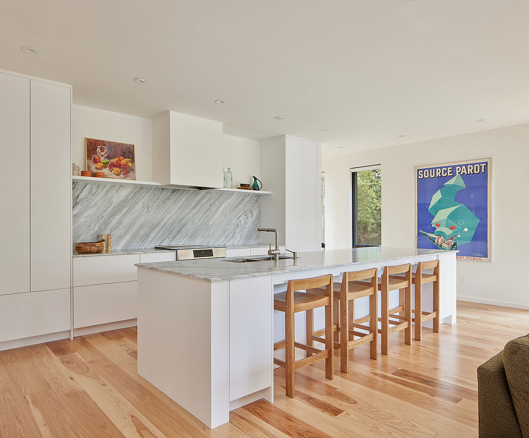 Modern kitchen with marble countertops, wooden stools, and colorful wall art.