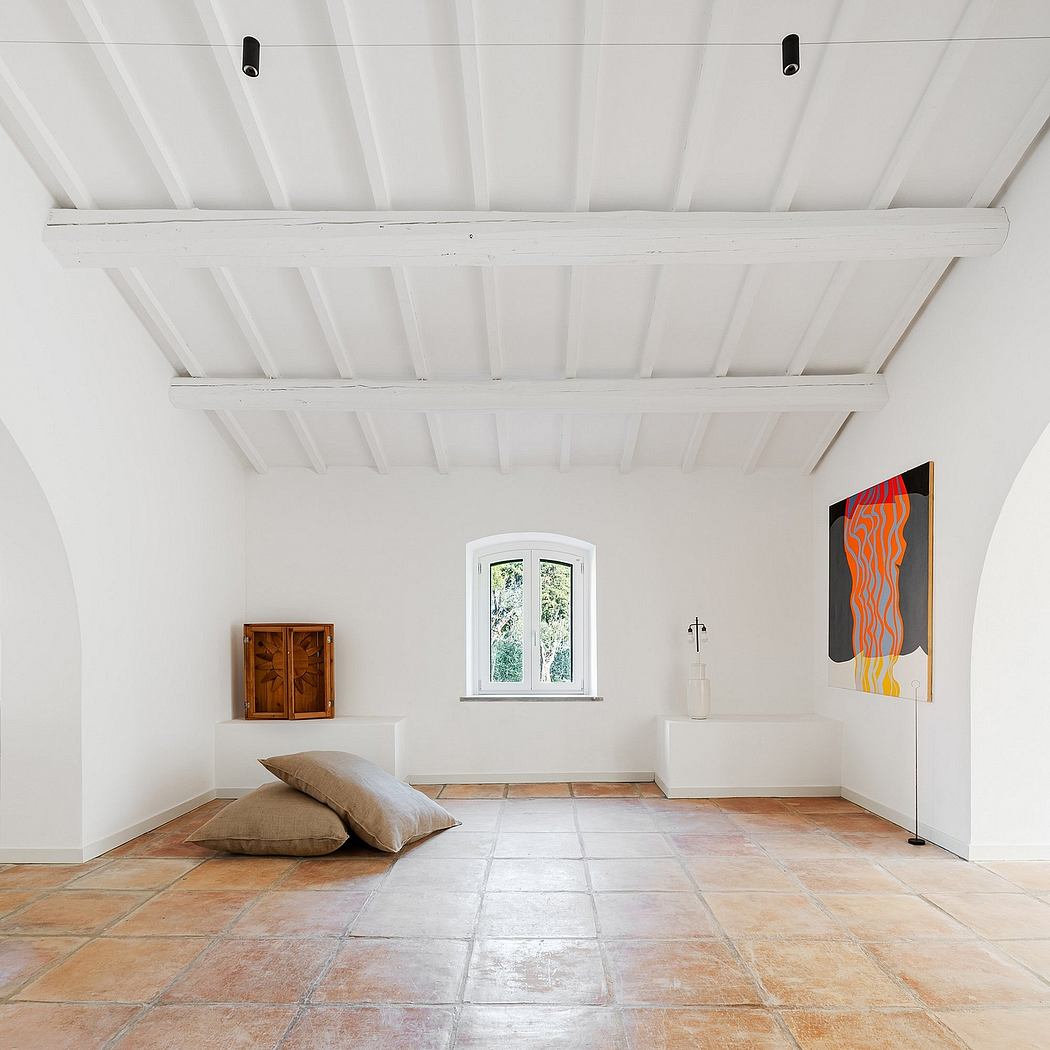 Spacious room with arched window, wood-beamed ceiling, and modern art display.