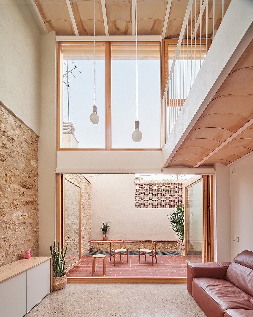 Warm, bright interior with exposed wooden beams, large windows, and tile flooring.