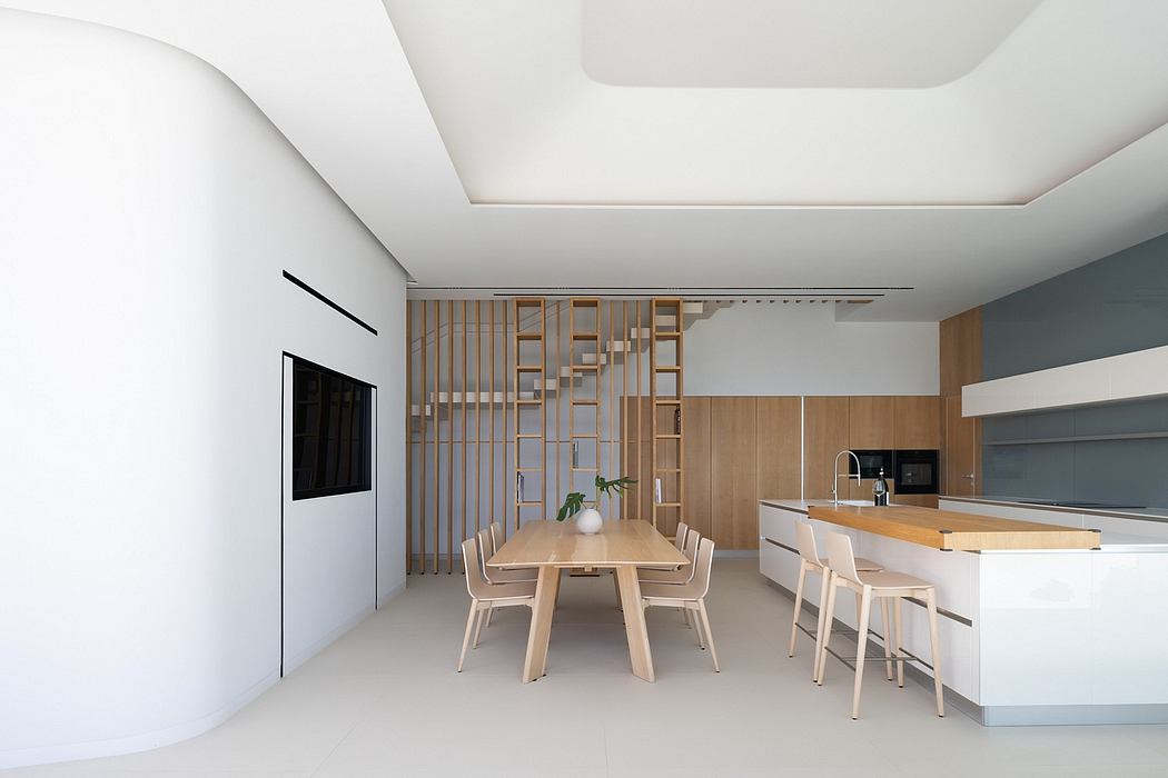 Modern, minimalist kitchen and dining area featuring wooden accents, clean lines, and a spacious layout.