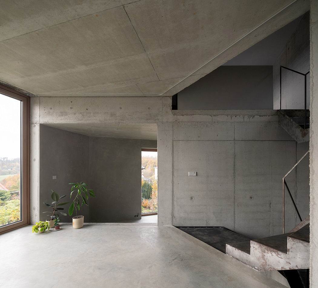 Minimalist concrete interior with large window, plant, and geometric architectural details.