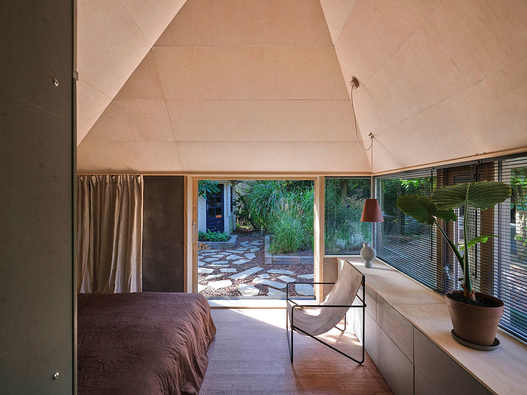 A spacious bedroom with a slanted ceiling, large windows, and a view of a lush outdoor landscape.
