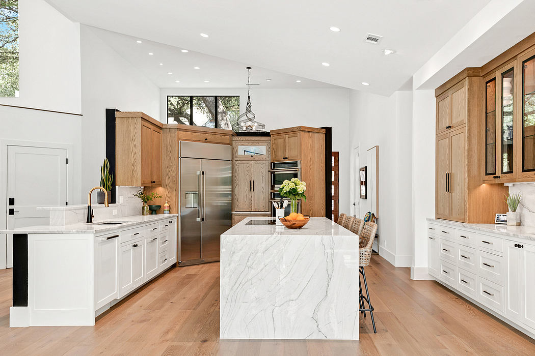 Spacious, open-concept kitchen with white marble countertops, wood cabinetry, and stainless steel appliances.
