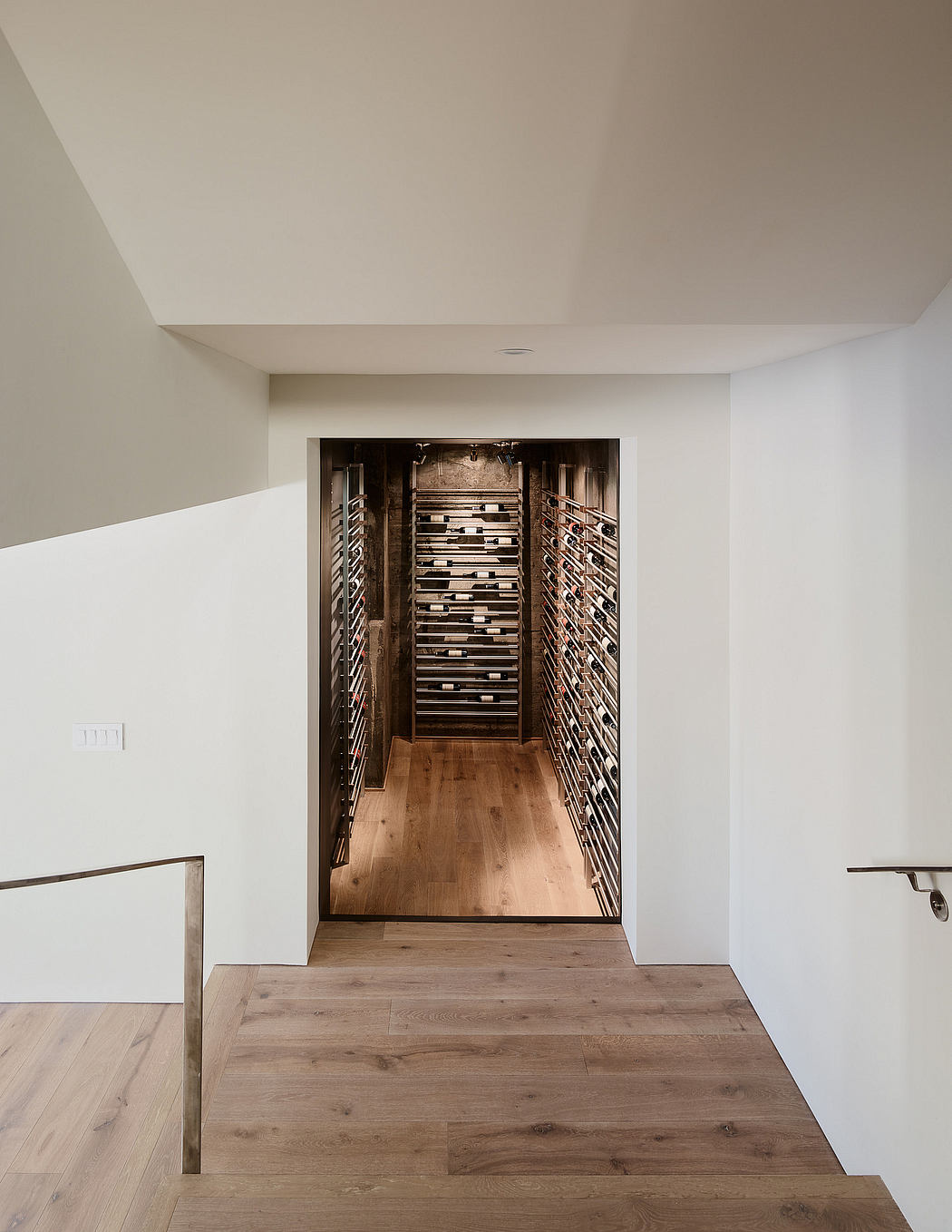 Expansive wine cellar with wooden shelves occupying a long, narrow space.