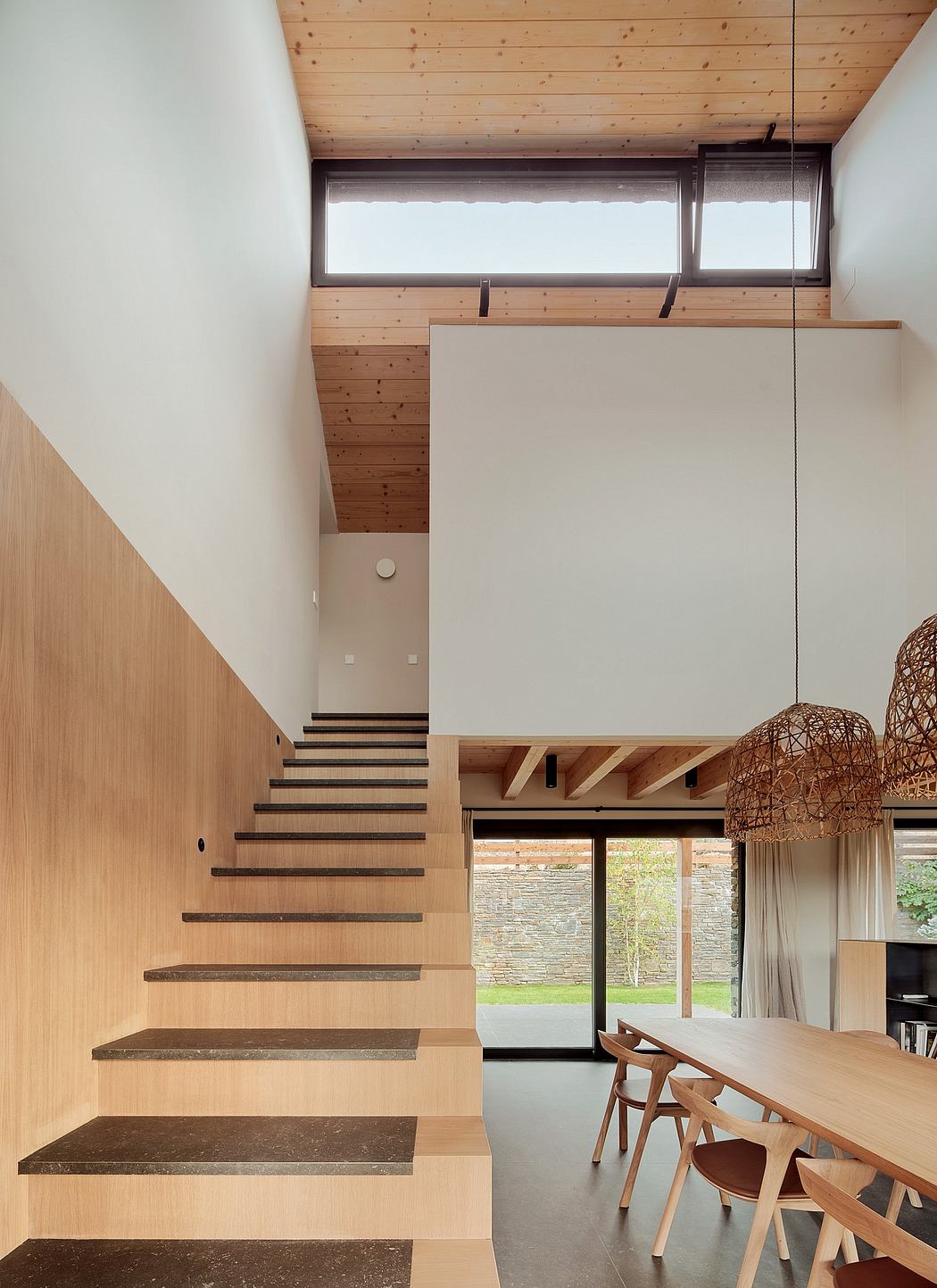 Wooden beams, stairs, and modern furniture in open-concept, light-filled space.
