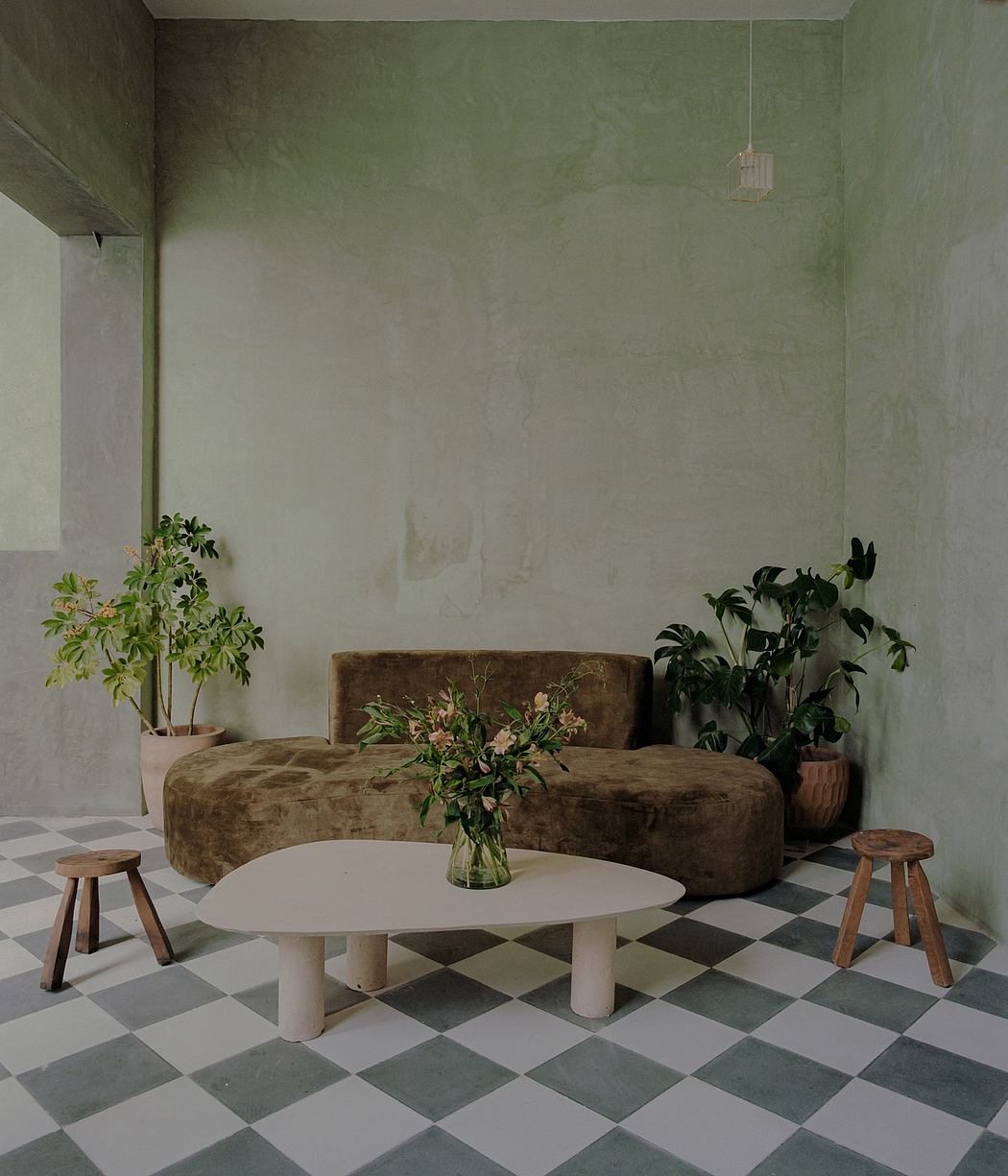 Minimalist living room with earthy tones, curved sofa, and checkered tile floor.