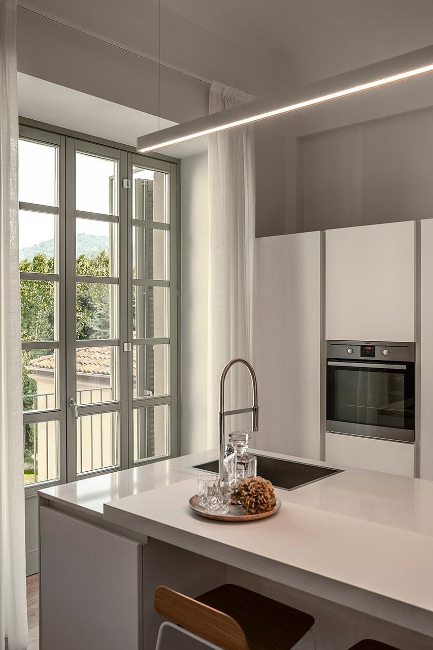 A modern, minimalist kitchen with large windows offering a scenic outdoor view.