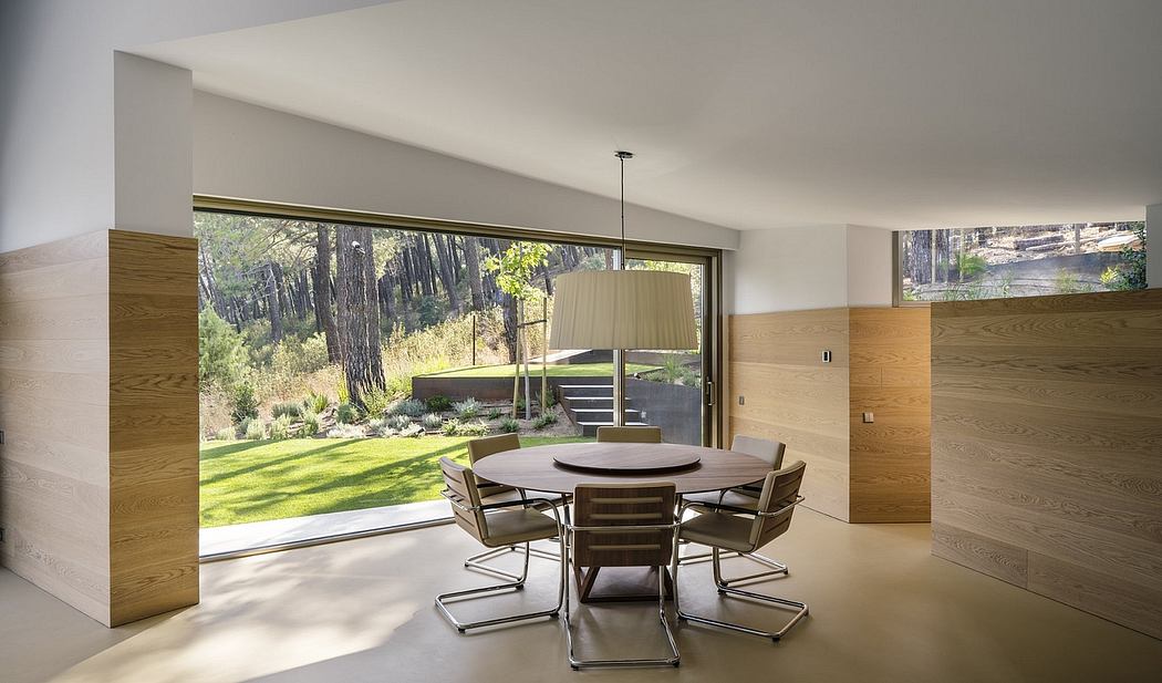 Minimalist dining area with wood-paneled walls, large windows, and a modern chandelier.