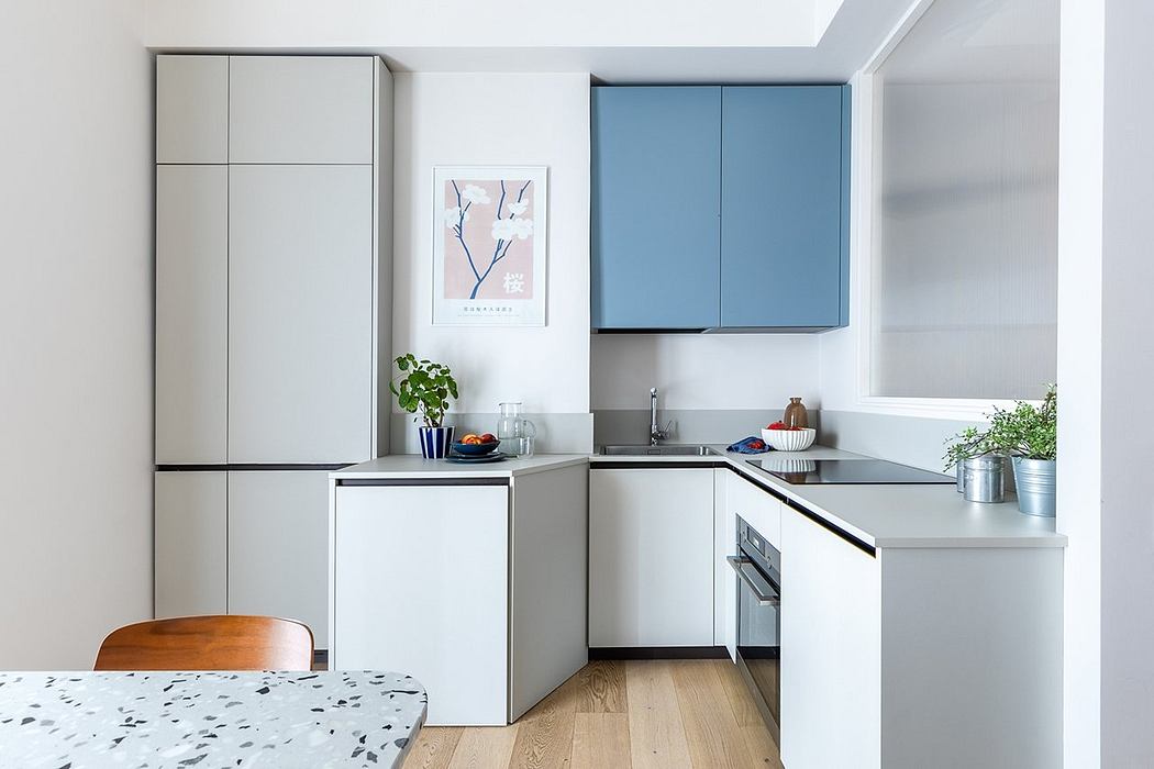 A modern, minimalist kitchen with sleek gray cabinets, a blue accent wall, and a wood dining table.