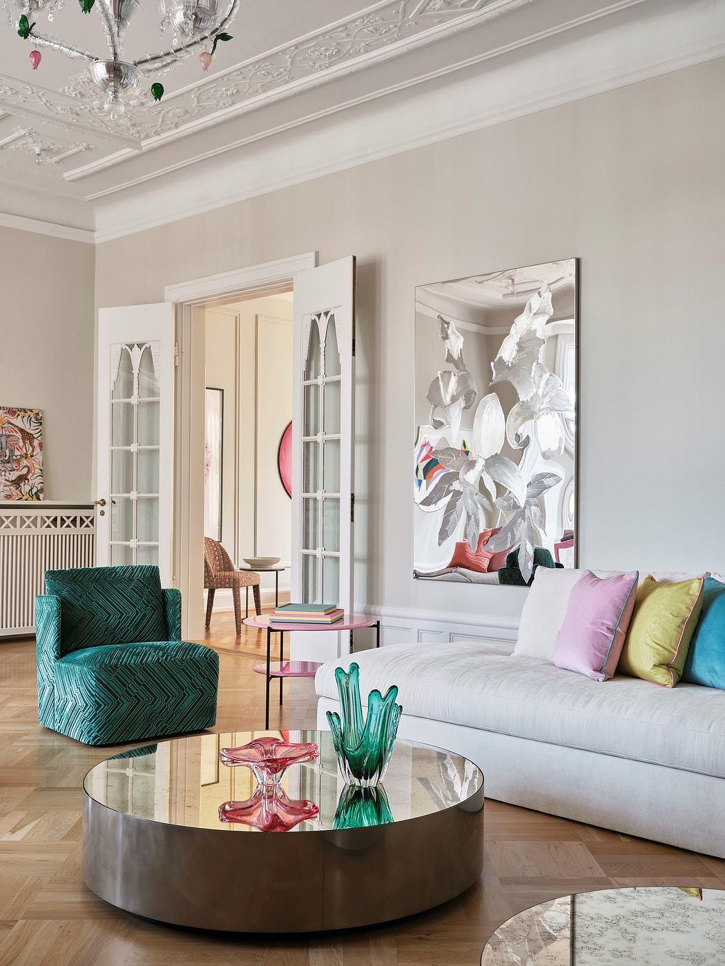 Ornate moldings, glass-paned doors, and a sculptural coffee table create a stylish, eclectic ambiance.