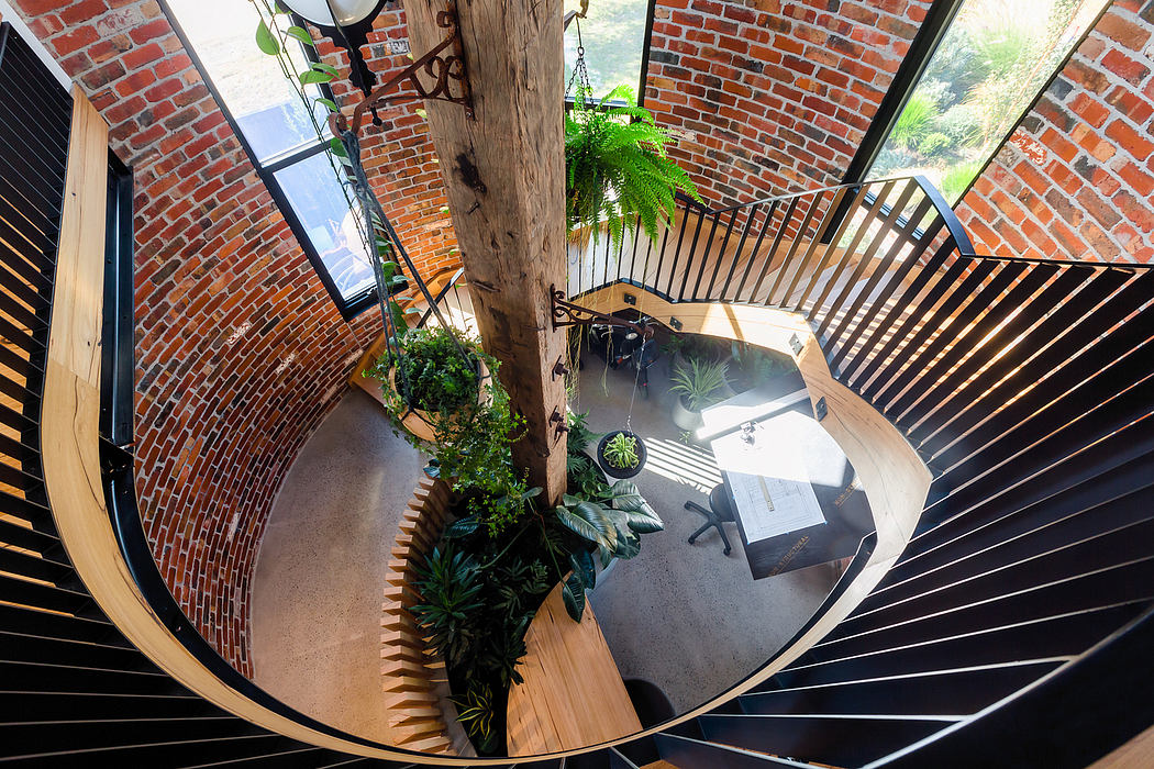 Spiral staircase with wooden and metal railings, framed by brick walls and potted plants.