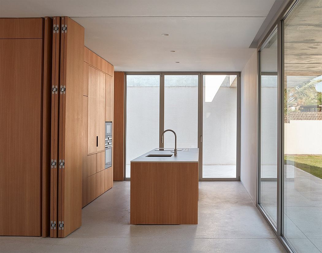 A bright, modern kitchen with wooden cabinetry, a central island, and expansive windows.