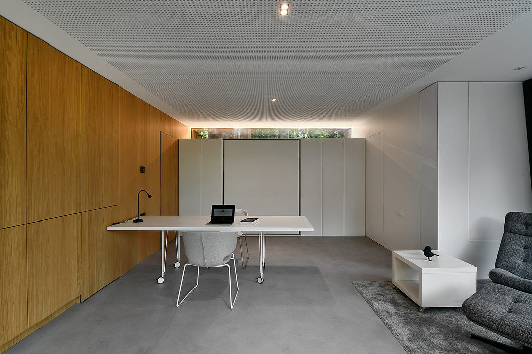 Minimalist home office with wooden panels, modern desk, and gray furniture.