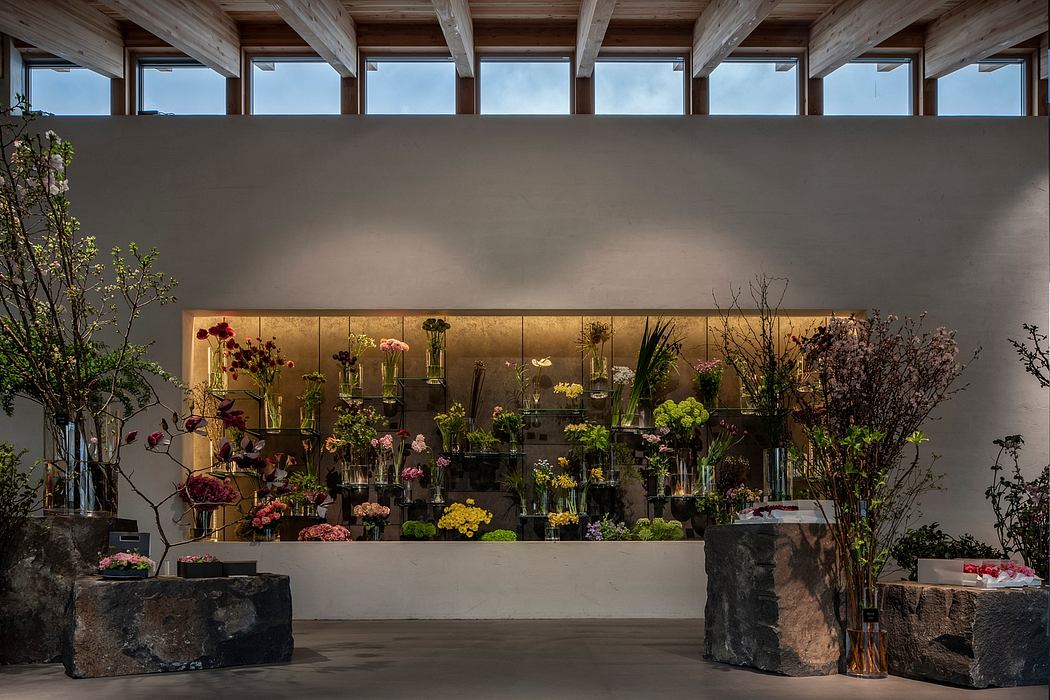 Warm, well-lit floral display with rustic wooden beams and stone wall backdrop.