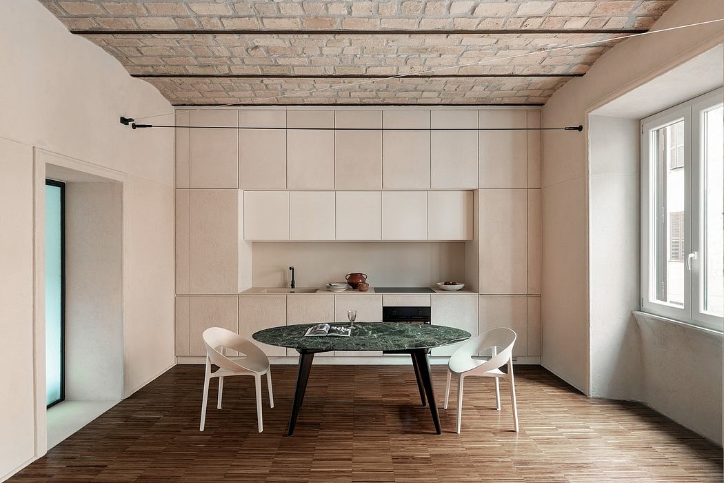 Minimalist kitchen with exposed brick ceiling, modern furniture, and a unique marble dining table.