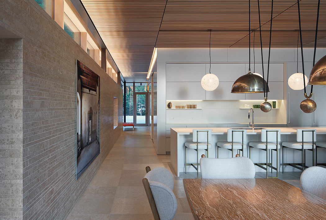 Modern open-concept kitchen with wood-paneled ceiling, pendant lighting, and minimalist decor.