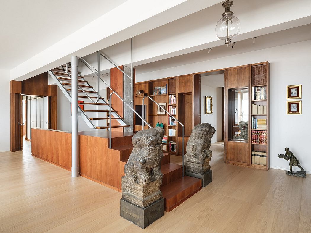 Spacious and modern interior featuring wooden stairs, bookshelves, and decorative statues.