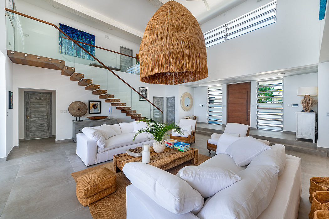 The image depicts a modern, open-concept living area with a large, woven pendant light and minimalist, beach-inspired decor.