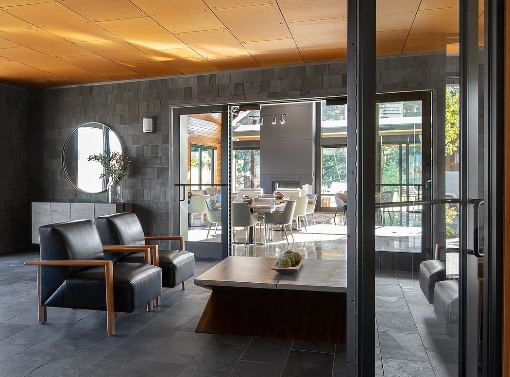 Modern open-plan living area with slate tile flooring, large windows, and contemporary furnishings.