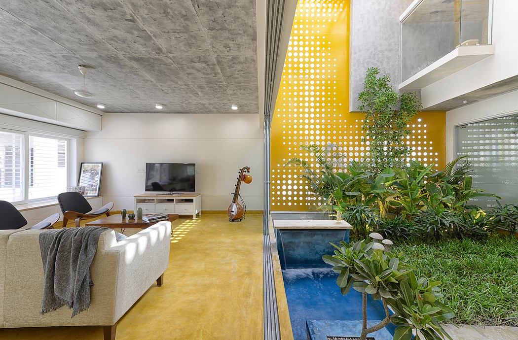 A modern living room with a vibrant yellow accent wall, potted plants, and concrete ceiling.