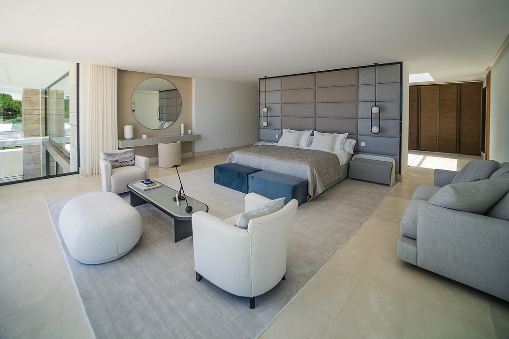A modern, open-concept bedroom with plush furnishings, textured walls, and floor-to-ceiling windows.