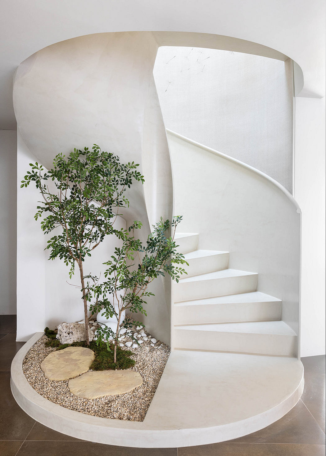 Minimalist white staircase with natural stone steps and a potted plant feature.