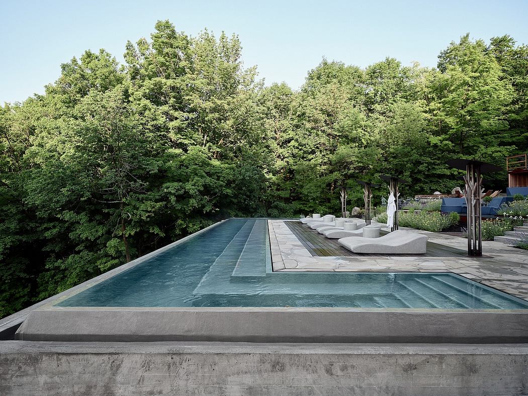 Tranquil outdoor swimming pool nestled amongst lush greenery and modern concrete design.