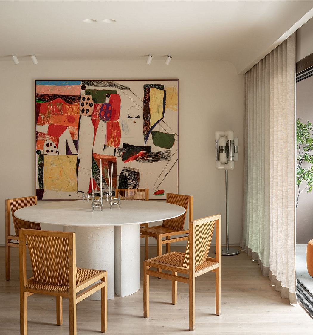 Contemporary dining room with a large abstract artwork, modern white table, and wooden chairs.