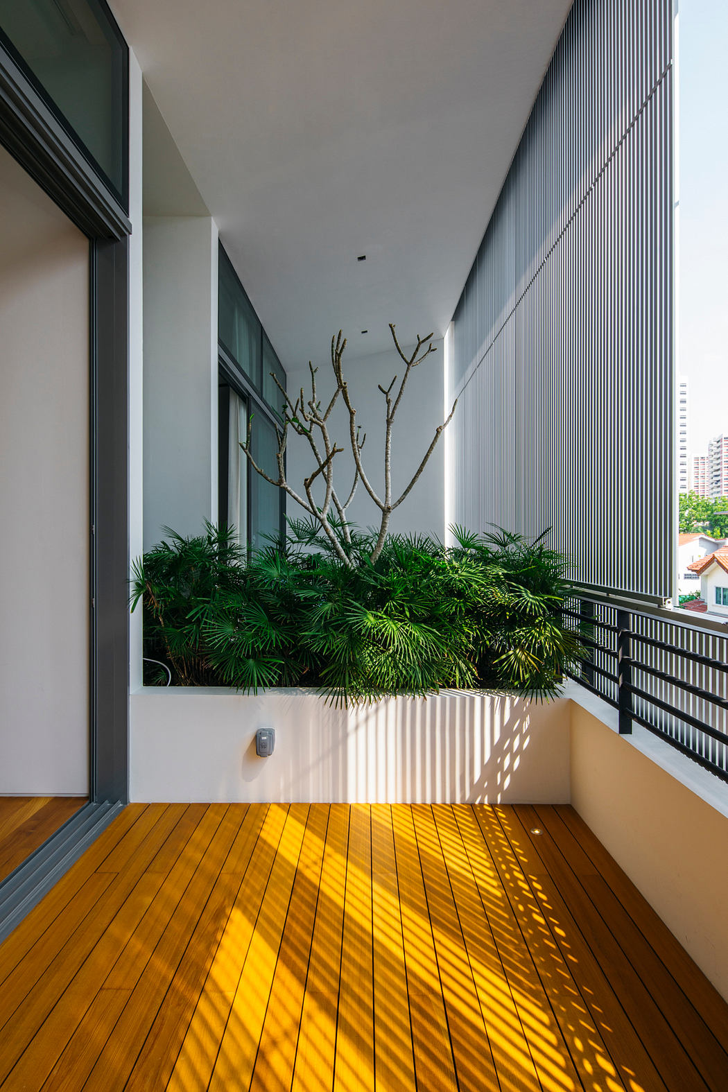 Spacious balcony with lush greenery, wooden floor, and modern architectural elements.