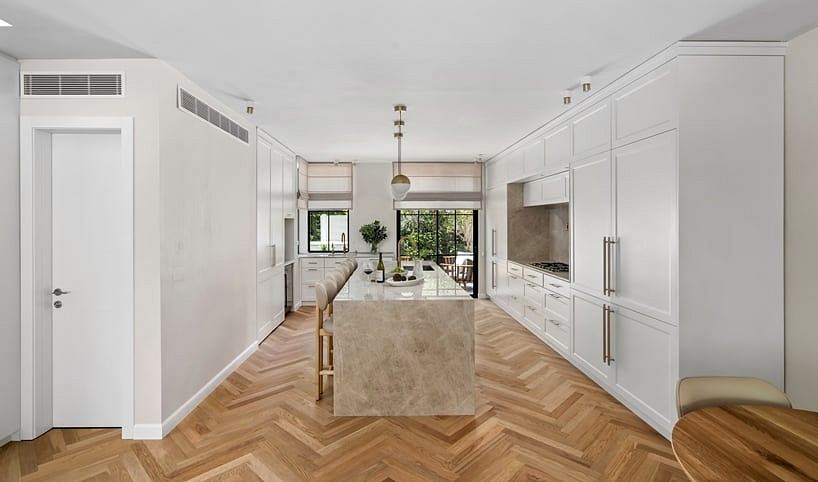Spacious, light-filled kitchen with modern cabinetry, herringbone wood flooring, and large windows.