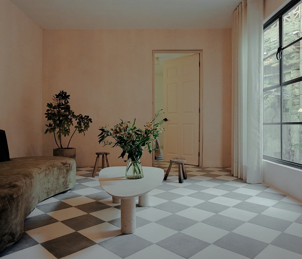 A spacious living room with a checkerboard tile floor, potted plants, and a glass-topped coffee table.