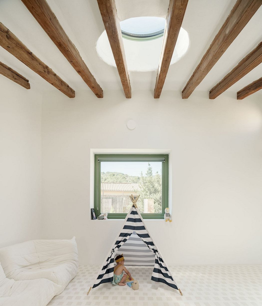 Cozy, airy space with wooden beams, a large window, and a striped tent for a child.