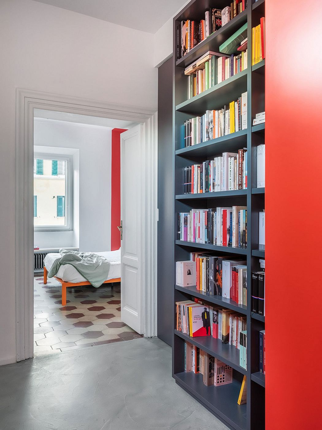 Vibrant bookshelves frame a cozy bedroom, complementing the patterned tile floor.
