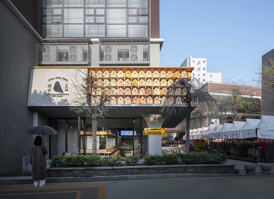 A modern building with a glass façade, decorative balconies, and outdoor seating areas.