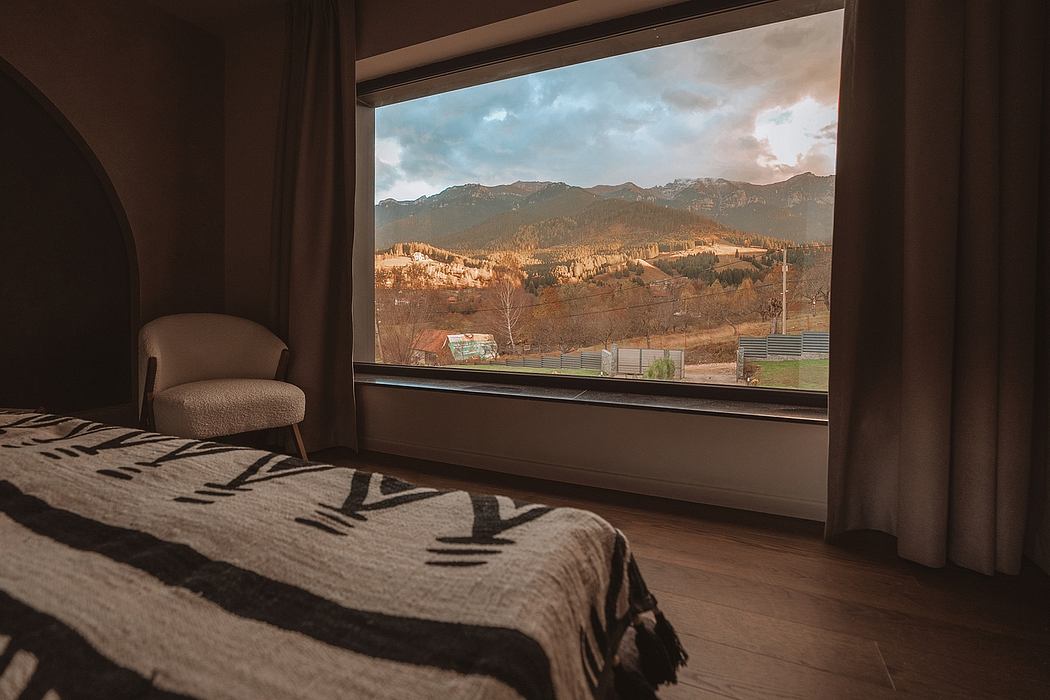 Cozy bedroom with large window overlooking picturesque mountain landscape.