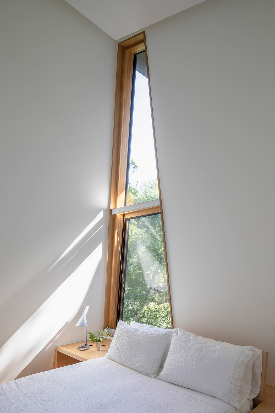 Bright, airy room with floor-to-ceiling wooden window offering serene garden view.