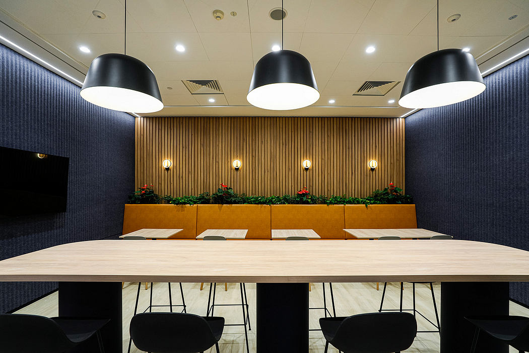 Sleek, modern meeting space with wooden paneling, low-hanging lamps, and a long table.