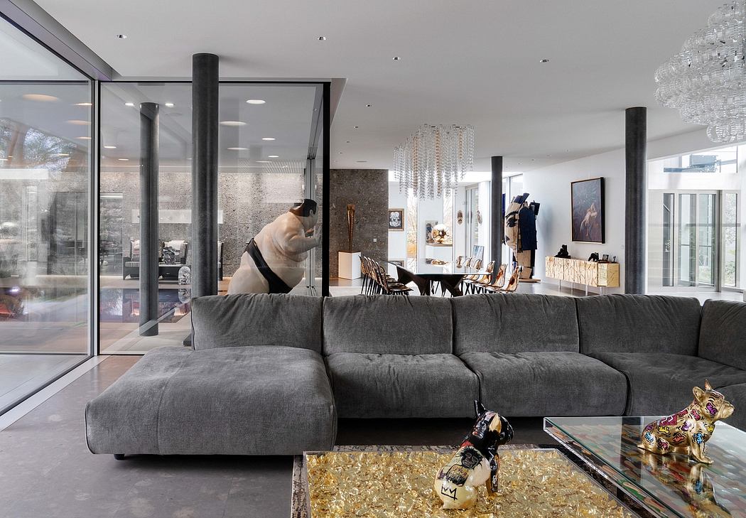 Sleek, modern interior with cozy gray sofa, glass walls, and elaborate chandelier.